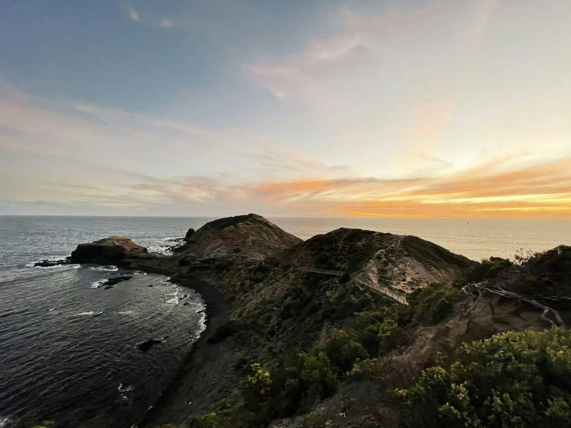 Coastal hills meeting the ocean at sunset