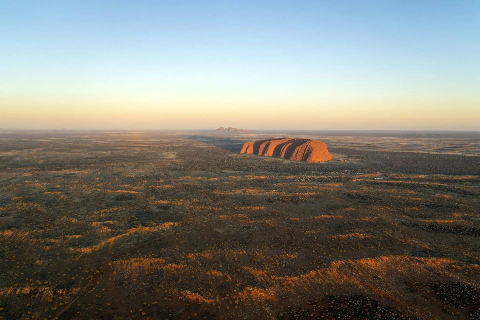 Uluru at sunset with vast desert landscape